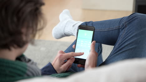 Relaxing at home, person using smartphone app for smart home control