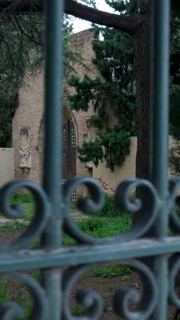 old brick archway and garden through a metal fence
