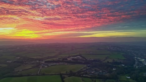 panning drone cinematic countryside scenery green misty fields colorful red sunset horizon fiery clouds