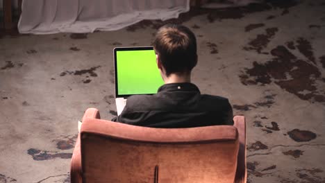 person working on a laptop with green screen