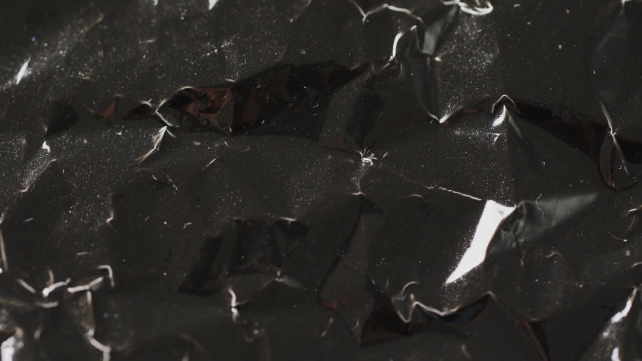 Close-up de saco de lixo plástico preto amassado em câmera lenta