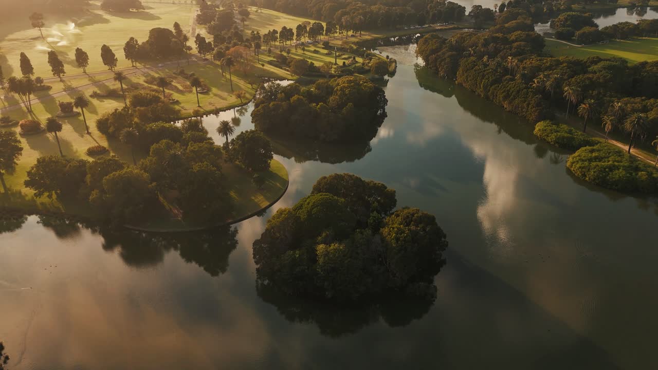 Golden light hitting lake and tree reflections in Centennial Park during sunrise or sunset, orbit, Sydney NSW Australia