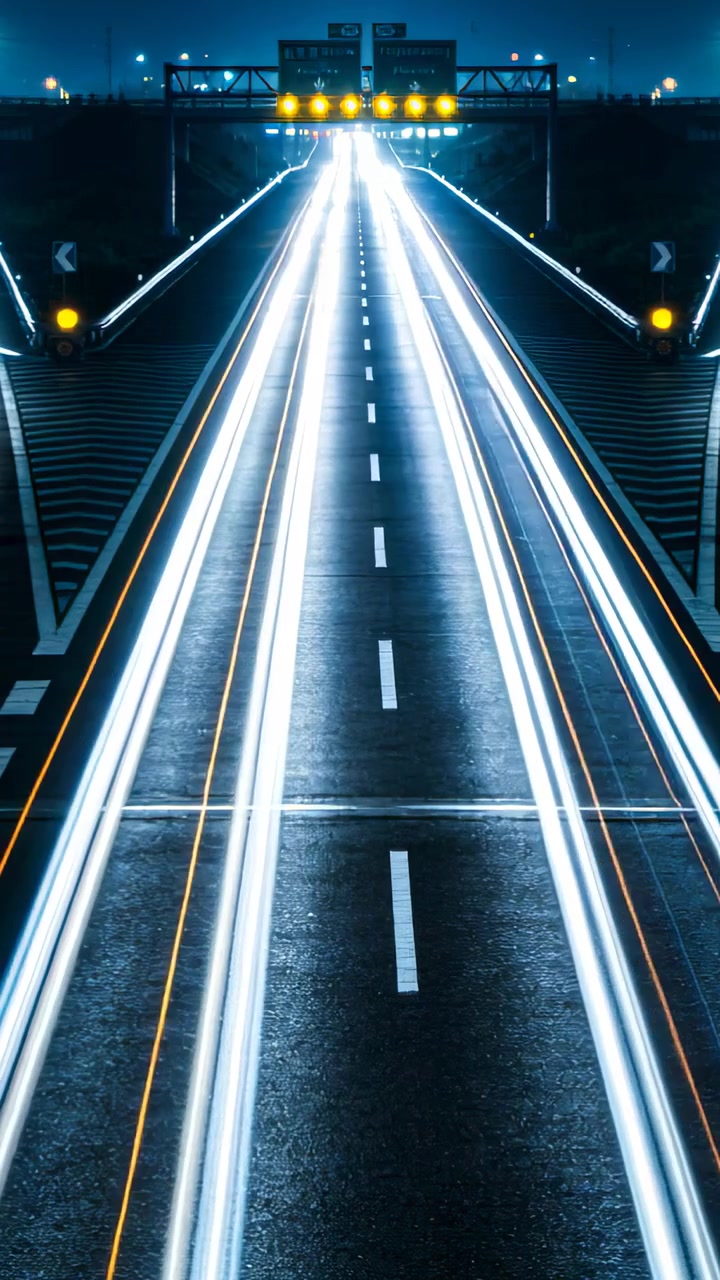 Video verticale: Riprese di un'autostrada sopraelevata di notte, con il traffico che si muove verso un portale e scie luminose.