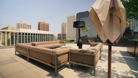 push in shot of a rooftop modern lounge with seating on a sky rise building in downtown city