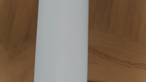 close up of propeller blade from a wind turbine looking down with an aerial drone, farmland fields in the background