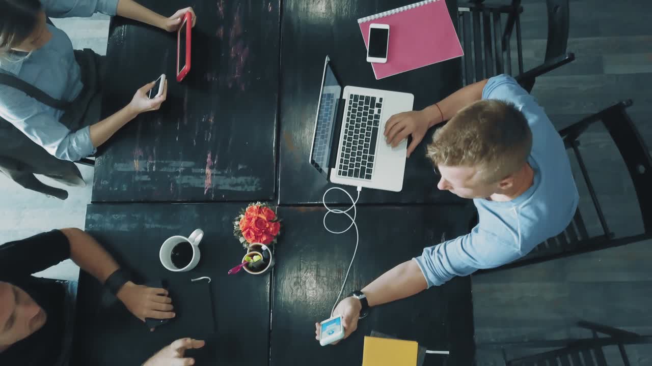 Vista dall'alto - scrivania di un team creativo aziendale che lavora su laptop e comunica usando smartphone in ufficio