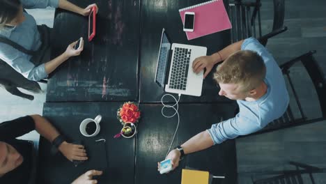 vista superior - escritorio de un equipo de negocios creativo que trabaja en portátiles y se comunica utilizando teléfonos inteligentes en la oficina.