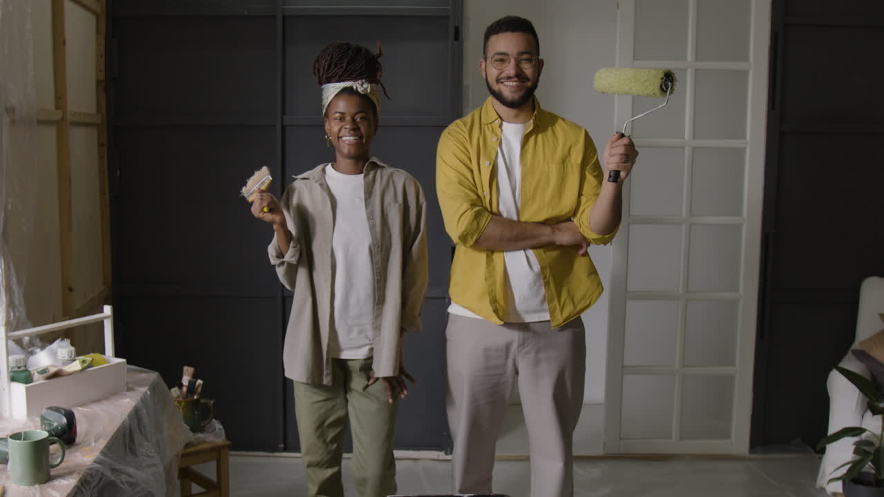 Couple Renovating Home with Paint Rollers and Brush