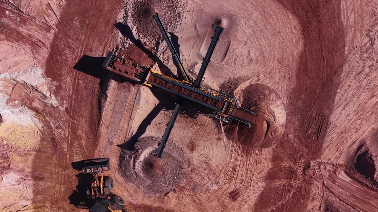 Overhead view of a multi-deck mobile screening plant with radial discharge conveyors separating clay and soil at an open-pit mining quarry