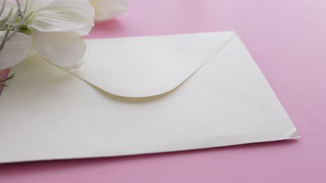 white envelope with flowers on pink background