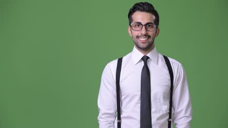 young handsome bearded persian businessman against green background