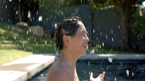 an asian young man is enjoying water splashing on his face