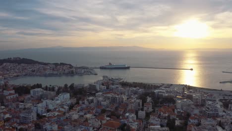 Vuelo-De-Drones-Sobre-El-Centro-De-Mitilini-Que-Revela-El-Amanecer-En-El-Mar-Con-Ferry-A-Atenas,-Lesbos,-Grecia