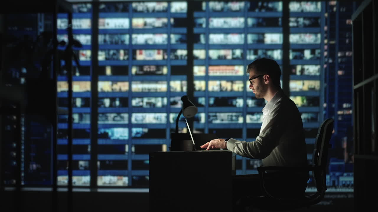 Portrait of Thoughtful Successful Businessman Working on Laptop Computer in His Big City Office at Night. Charismatic Digital Entrepreneur does Data Analysis for e-Commerce Strategy