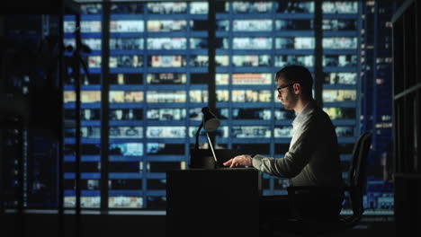 portrait of thoughtful successful businessman working on laptop computer in his big city office at night. charismatic digital entrepreneur does data analysis for e-commerce strategy