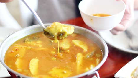 ladling soup into a bowl at a table