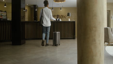 Woman-checking-in-at-the-hotel-reception-desk
