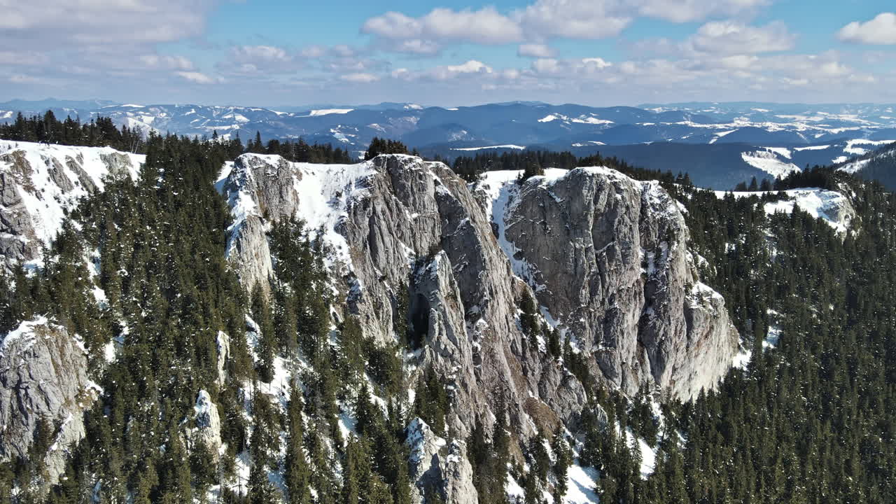 Vista aerea dei Carpazi in primavera, Romania, ripresa da un drone. Cime rocciose e valli parzialmente coperte da foreste innevate