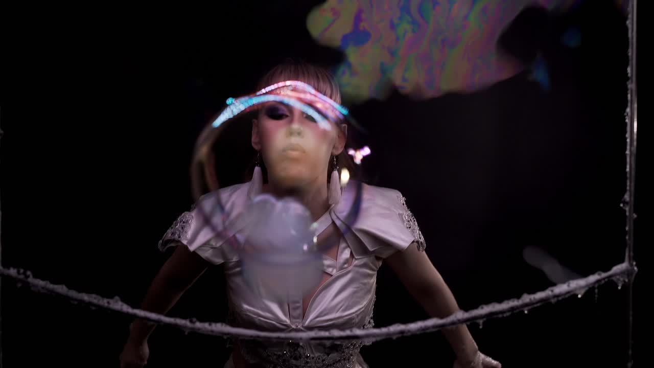 cerca chica linda hace trucos con burbujas de jabón ella sopla una burbuja de su mano hacia el espectador