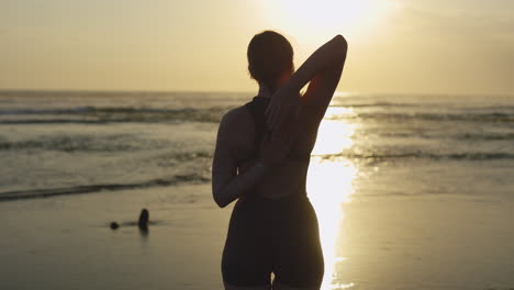 woman stretching on beach at sunrise