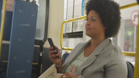 happy plus size biracial woman using smartphone in bus