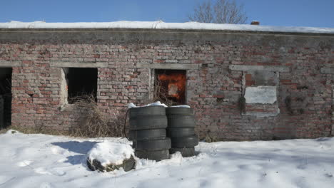 bomb blast explodes in old brick building with tires stacked outside in snow