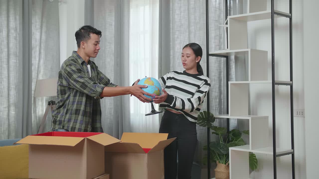 커플이 상자를 열고 새로운 집의 장식을 정리하고 있습니다.