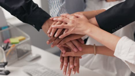 hands of different nationalities, skin colors, stacked one on top of the other over the office desk, an agreement, a close-knit team, working together, a bet, all for one