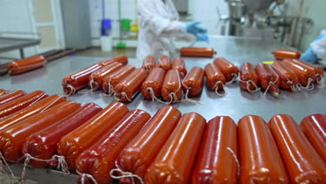 loaves of freshly-made soft cheese at the metal table. two workers finishing the packaging of dairy product. ready-made cheese in orange package close up.