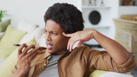 happy african american man using smartphone at home