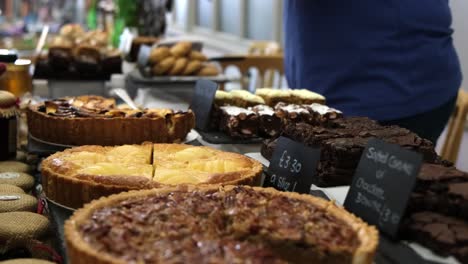 puesto de panadería con pasteles calientes y brownies de chocolate exhibidos en el mercado de alimentos en londres