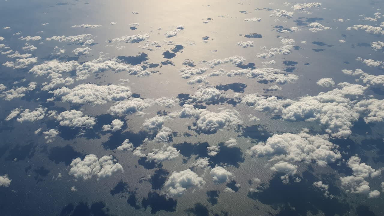 aéreo de arriba hacia abajo de pequeñas nubes que se reflejan en el mar y se mueven