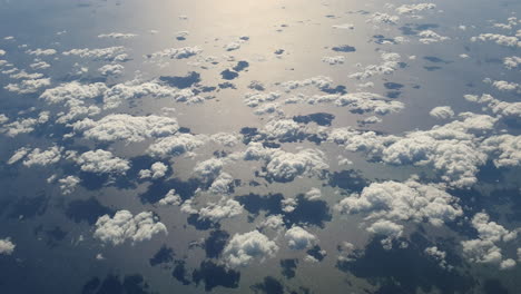 Antenne-Von-Oben-Nach-Unten-Von-Kleinen-Wolken,-Die-Auf-Dem-Meer-Reflektieren-Und-Sich-Bewegen