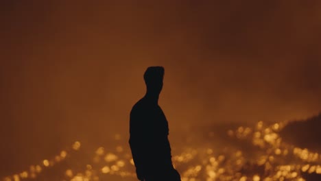 pacaya volcano, guatemala - a silhouette of a man with a headlamp striking a pose near the rivers of molten lava at night - handheld shot