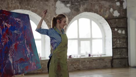 Female-artist-emotionally-dancing-in-front-of-abstract-painting-in-studio-in-slowmo