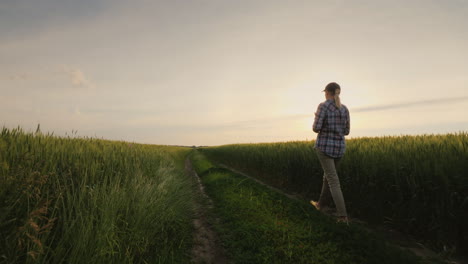 A-Female-Farmer-Walks-Along-A-Country-Road-Along-Wheat-Fields