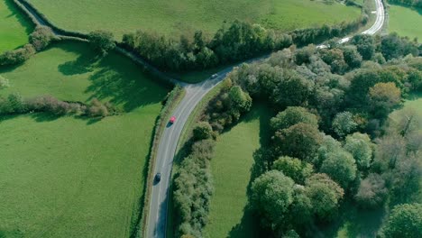 Three-cars-drive-in-one-direction-with-equal-distance-along-a-quaint-British-countryside-road