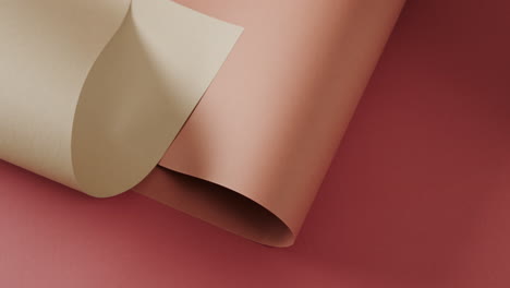 Close-up-of-two-shades-of-brown-rolled-papers-on-red-background-with-copy-space-in-slow-motion