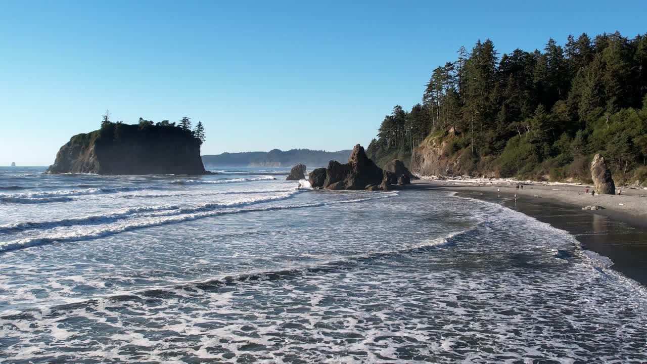 toma aérea de olas rompiendo en la playa con gente disfrutando del paisaje