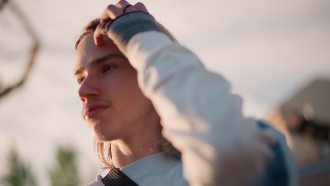 Ungdommelig indie-stemning. Mykt kantlys skaper en reflekterende stemning. Gitarist under «golden hour» med karusellbakgrunn i uskarphet. Portrett av ung musiker med mildt lys og reflekterende atmosfære