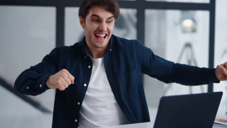 surprised man getting good news on laptop in office