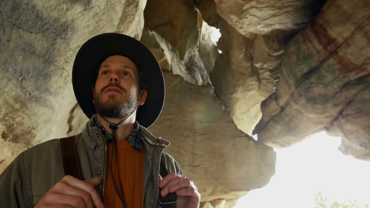 동굴 4k에서 배 ⁇ 과 함께 서있는 남성 하이커