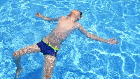 teenager on vacation in swimming pool. boy play and swim in resort pool on summer family vacation