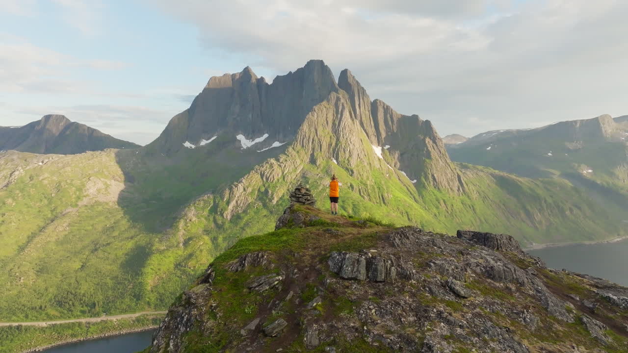 Drone crane reveal jagged arctic senja mountain with hiker in foreground
