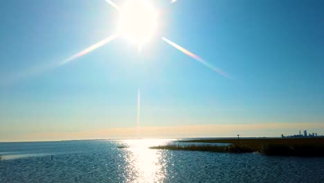 HD-MOTIONLAPSE-pan-left-to-right-from-sun-and-sun-reflecting-on-waterway-to-Atlantic-City-skyline-in-distance-on-a-nice-clear-day,-also-available-in-4K