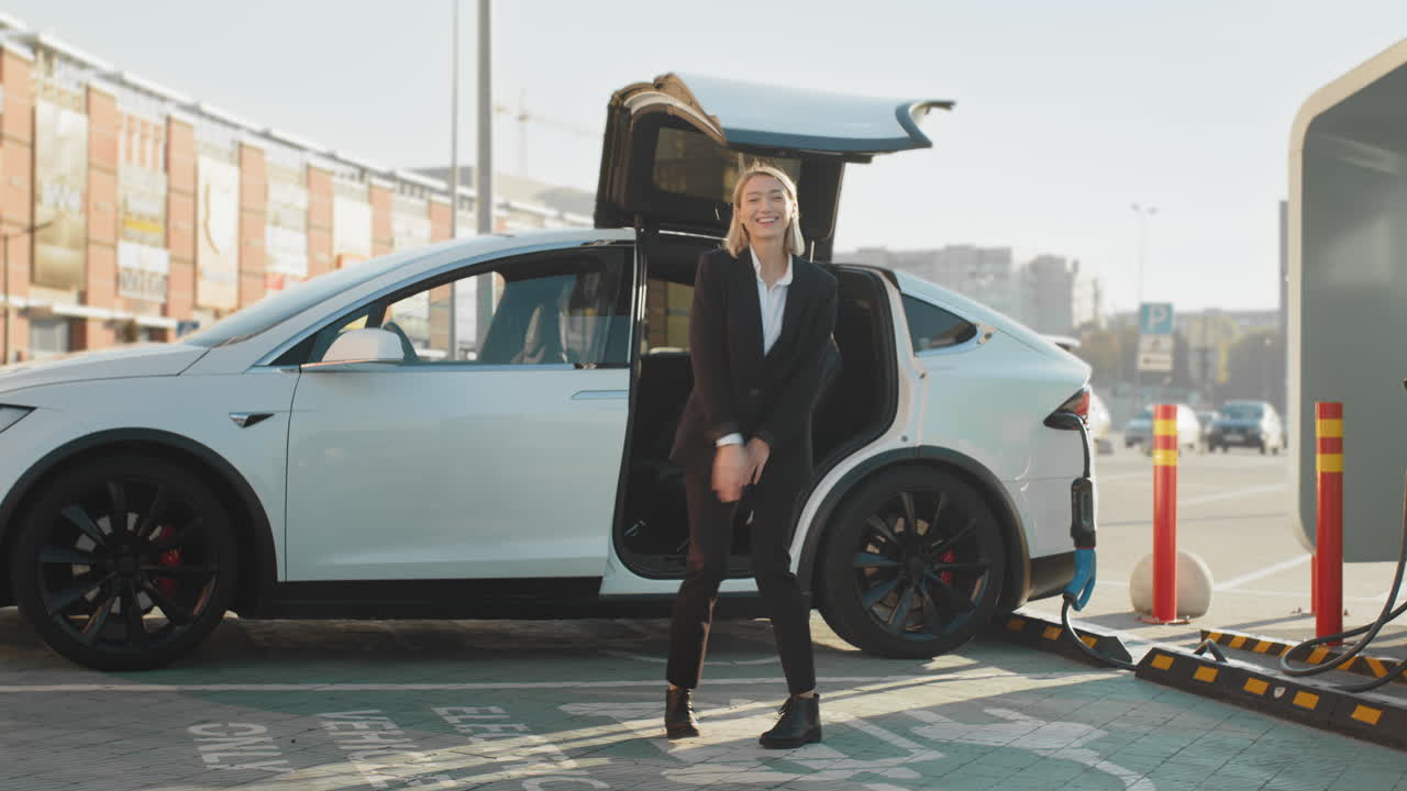 충전소 에서 전기 자동차 근처 에서 춤을 추는 여자