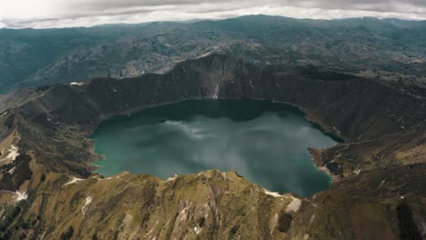 vista aérea cinematográfica sobre el paisaje del volcán y el lago del cráter durante el día nublado en ecuador