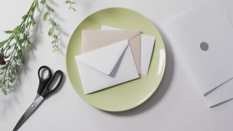 Video-of-scissors-and-plate-with-envelopes-on-white-background
