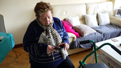 modern granny attaching a smartphone to a selfie stick to take pictures of herself at home