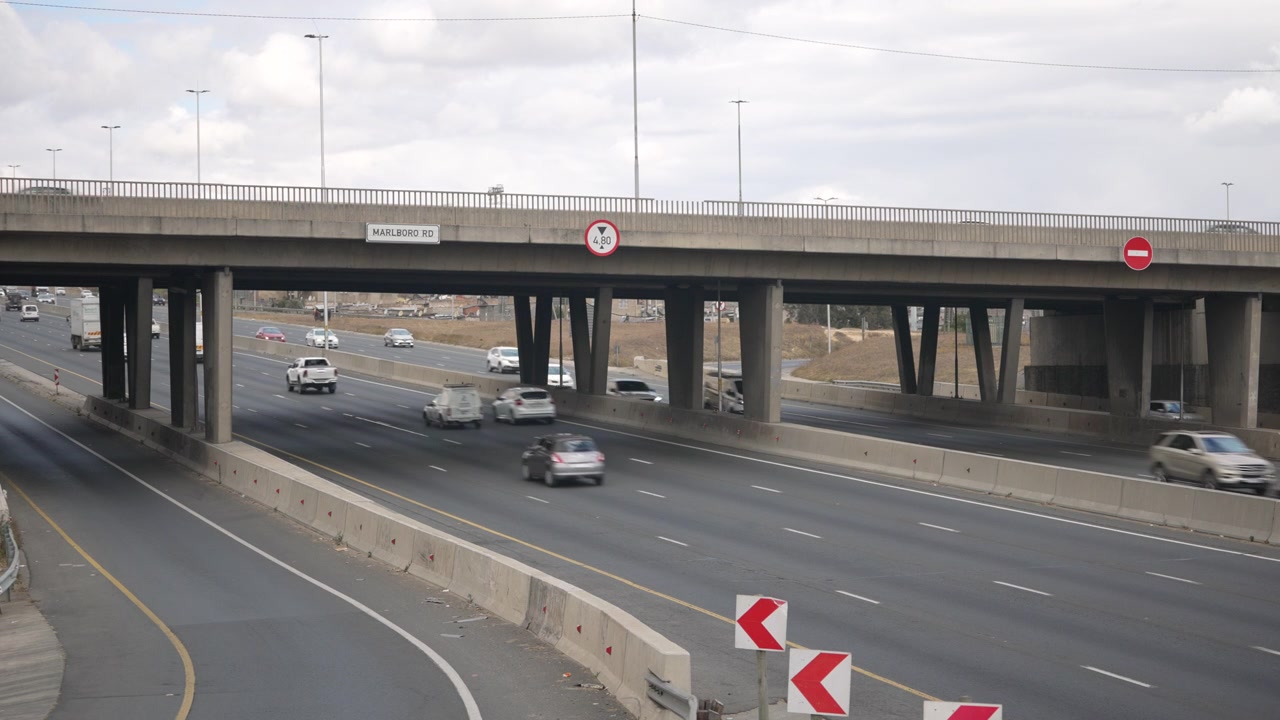 Coches y camiones viajan rápidamente bajo el puente de la autopista N1 con cielos nublados arriba. Adecuado para planificación urbana o proyectos de transporte.